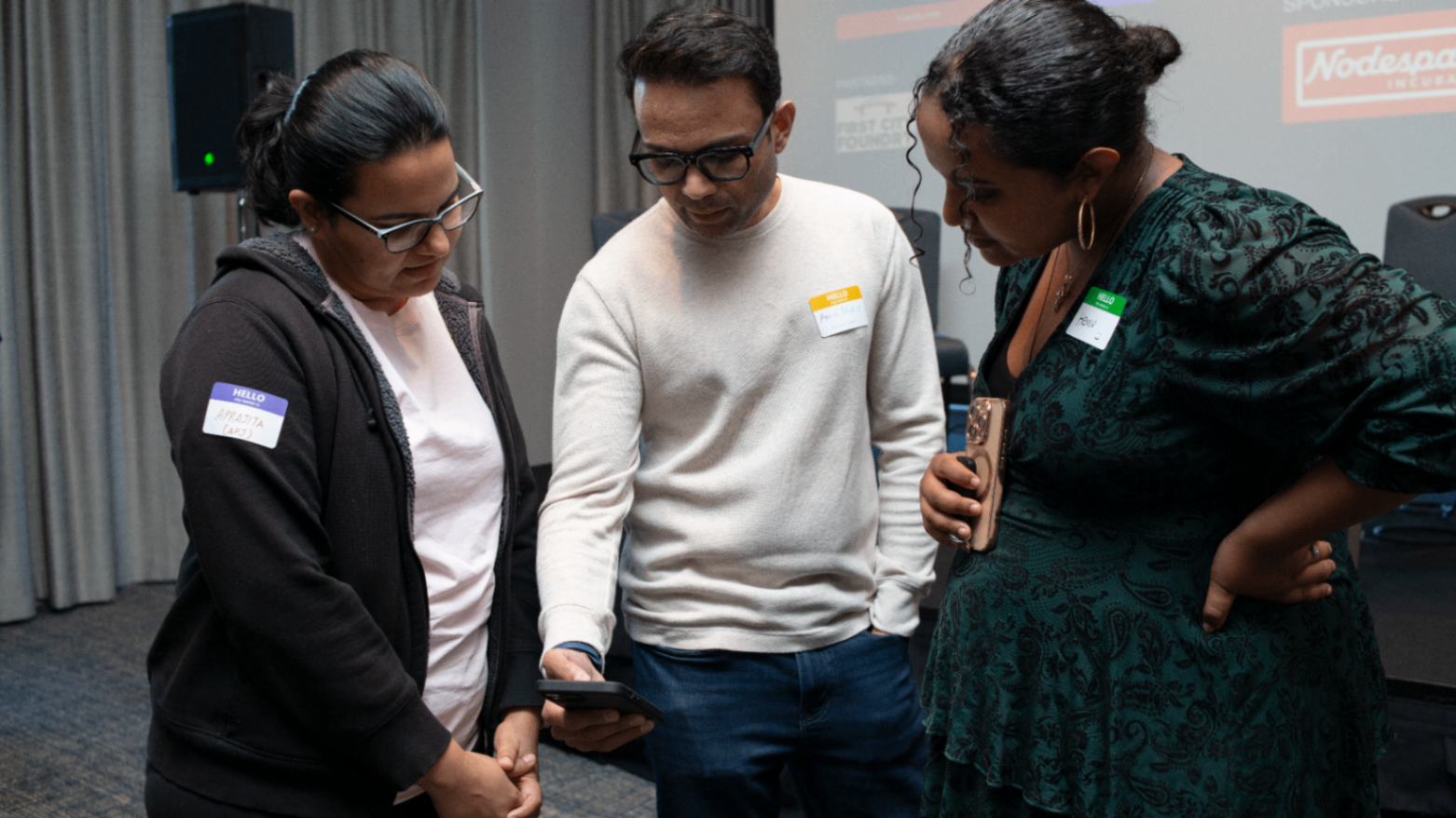 Three attendees reviewing something together on a phone