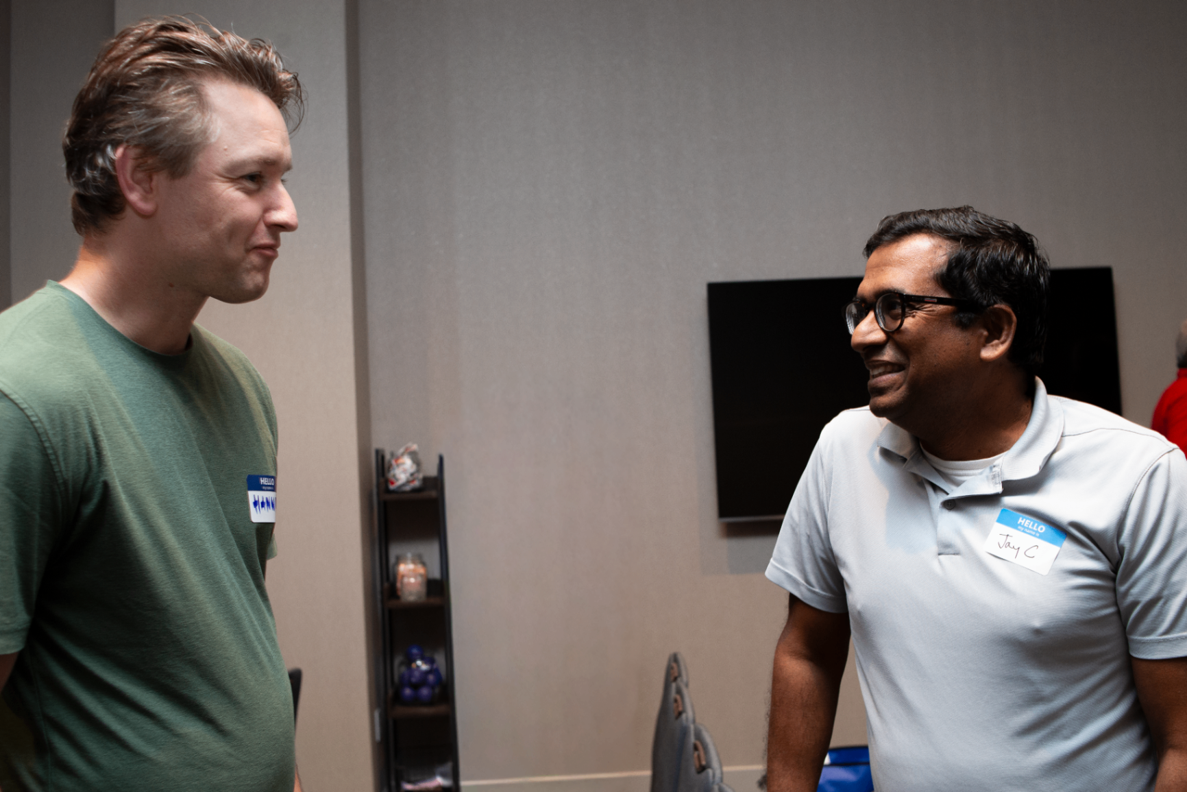 Two attendees smiling during a hallway conversation