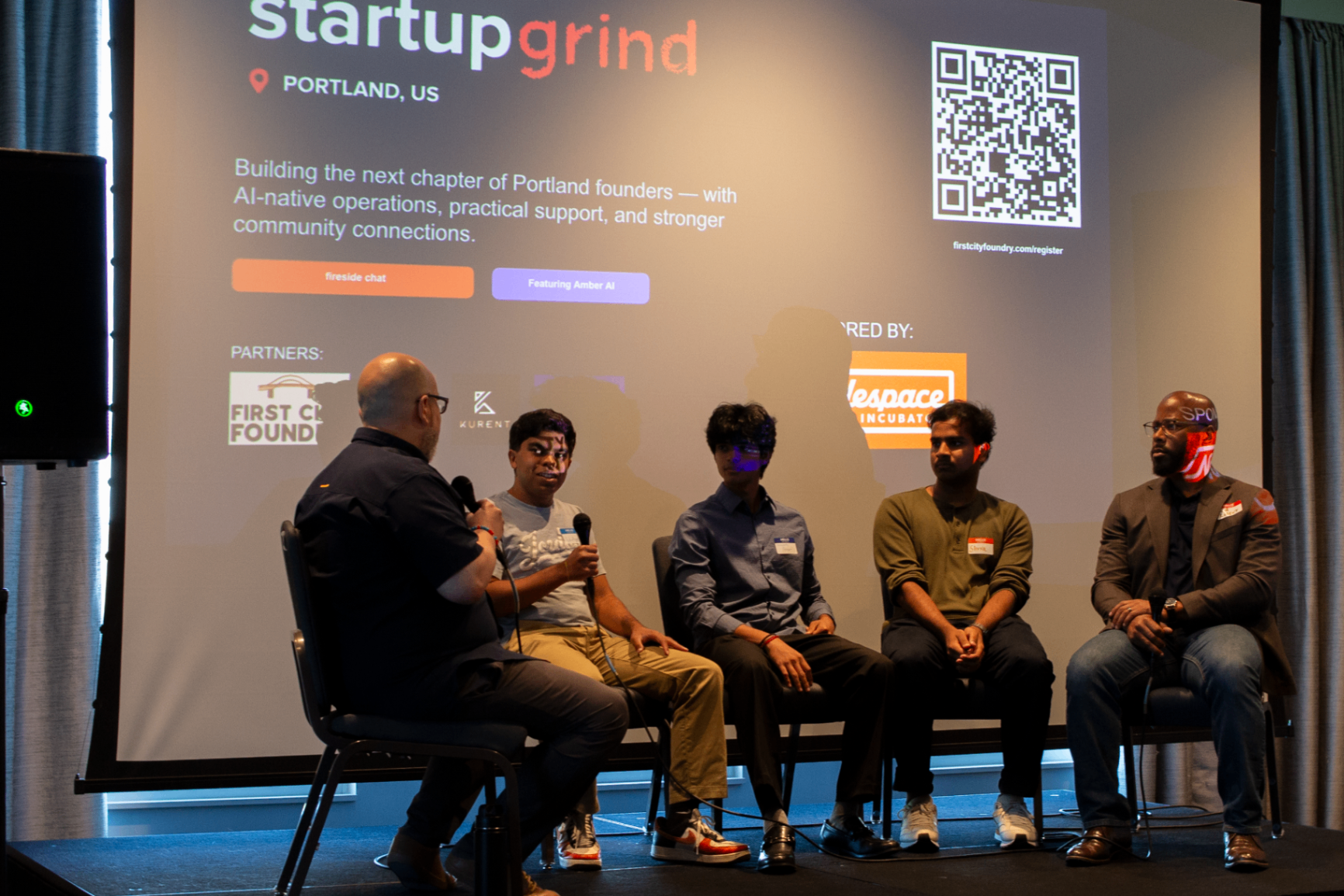 Wide stage shot of a Startup Grind Portland panel with projection screen